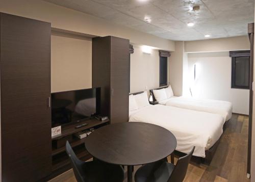 a hotel room with a table and a bed and a tv at Prime Suites Tokyo in Tokyo
