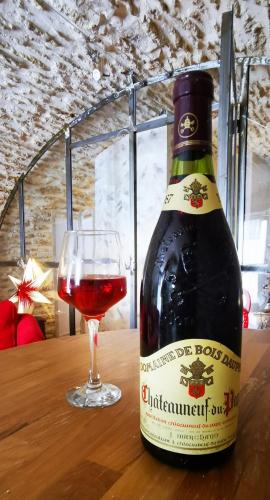 - une bouteille de vin à côté d'un verre de vin dans l'établissement Chambre d hote de charme avec plein d authenticité du 13 ème siècle, à Châteauneuf-du-Pape