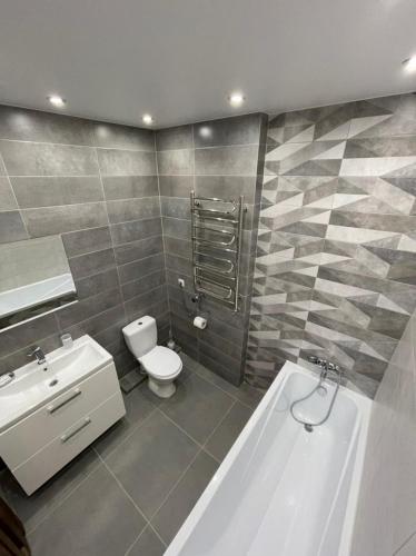 a bathroom with a toilet and a sink and a tub at White House apartment in Lviv