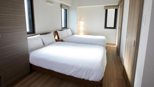 1 dormitorio con 2 camas y 2 ventanas en Prime Suites Tokyo, en Tokio