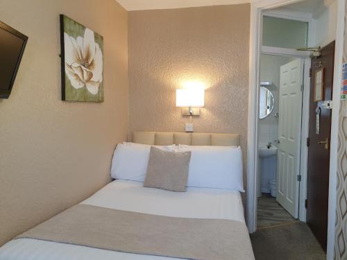 a bedroom with a bed with white sheets and a lamp at Corona Blackpool in Blackpool