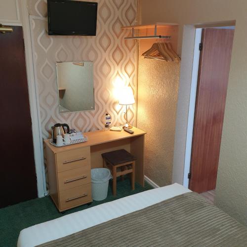 a bedroom with a bed and a desk with a mirror at Corona Blackpool in Blackpool