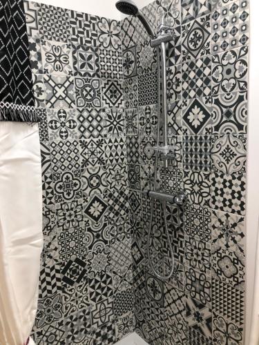 y baño con ducha y azulejos blancos y negros. en Muratello Appart 1, en Porto Vecchio