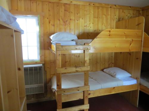 two bunk beds in a wooden room with a window at HI Rampart Creek - Hostel in Saskatchewan River Crossing