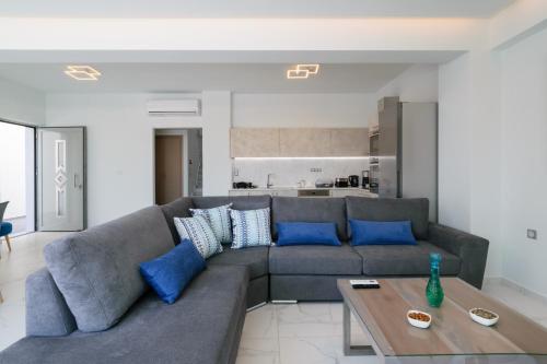 a living room with a gray couch and blue pillows at Katakis LuxuryVillas in Chania