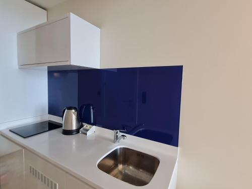 cocina con fregadero y pared azul en Hotel Orbi City Sea Horizon en Batumi