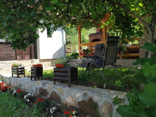 a garden with two chairs and a fire place at Rustična kuća CRVENA STENA u blizini kućice na Drini in Bajina Bašta