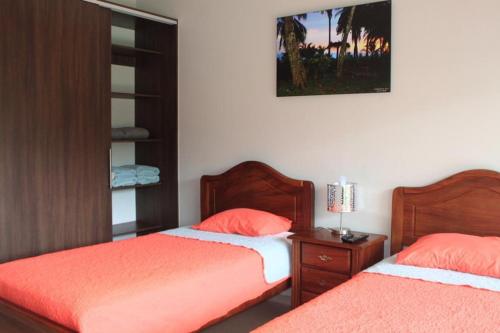 um quarto com 2 camas com lençóis laranja e uma mesa de cabeceira em Amaluc zac em Jacó