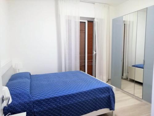 een slaapkamer met een blauw bed en een spiegel bij via Ancona a 50mt dal mare in Marcelli