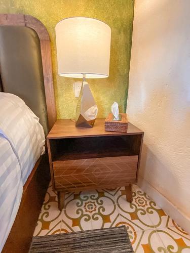 a nightstand with a lamp on it next to a bed at Hotel Boutique Santo Cuervo in Bernal