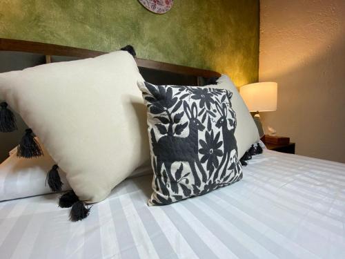 a bed with black and white pillows on it at Hotel Boutique Santo Cuervo in Bernal