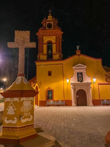 a yellow church with a cross in front of it at Hotel Boutique Santo Cuervo in Bernal