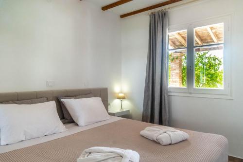 a bedroom with a bed with white pillows and a window at Terracotta beach house in Lefkímmi