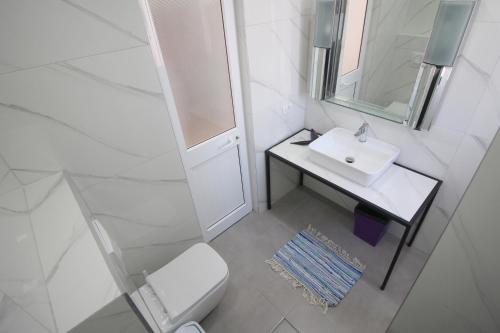 a white bathroom with a sink and a mirror at Olympia Hotel in Sarandë