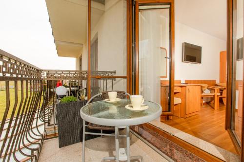 Cette chambre dispose d'une table en verre et d'un balcon. dans l'établissement Willa Karolinka, à Dziwnówek