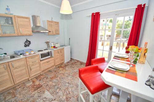 a kitchen with a table with a red chair and a counter at Mike's apartments in Agios Gordios