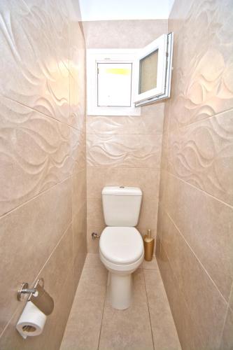 a small bathroom with a toilet and a window at Mike's apartments in Agios Gordios