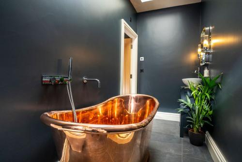 a copper tub in a bathroom with plants at The Courtyard in Chichester