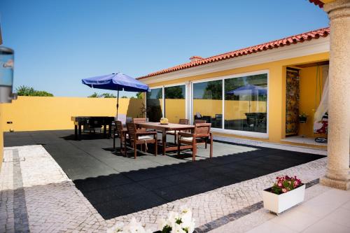a patio with a table and chairs and an umbrella at Quinta Salinas - Puro Prazer in Aveiro