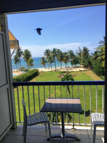 a table and chairs on a balcony with a view of the beach at Studio vue mer Le Gosier sans coupure d'eau in Le Gosier
