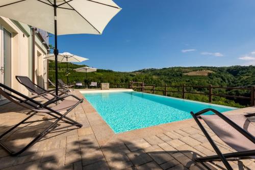 a swimming pool with two chairs and an umbrella at Cascina Pajanòt in Benevello