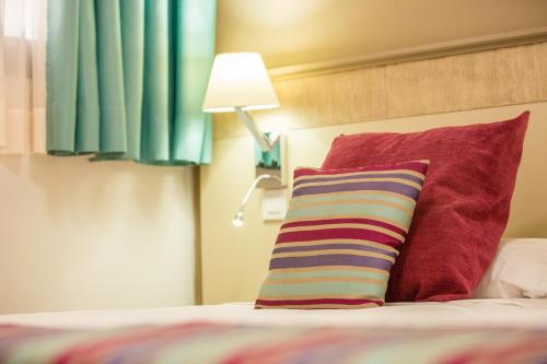 a bed with two red pillows and a lamp at Amadores Beach Apartments in Mogán