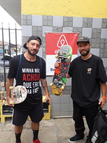 two men are holding their skateboards in front of a building at Perto Do Aeroporto De Salvador - Dona Pitanga Hostel in Lauro de Freitas