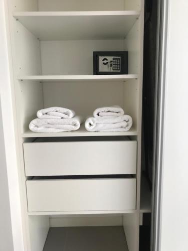 a closet with white towels and a clock at Depto en Complejo Ciudad Gama in Cordoba