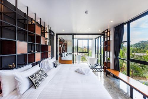 1 dormitorio con 1 cama blanca grande y ventanas grandes en Book a Bed Poshtel - SHA Plus en Phuket