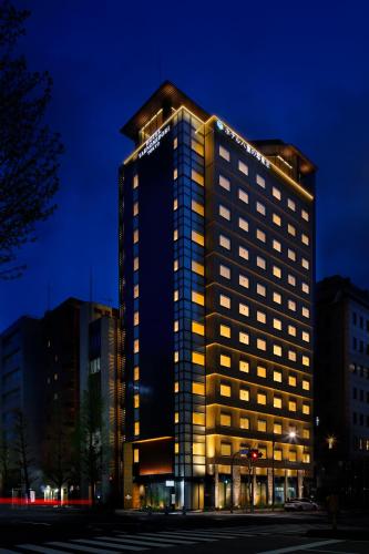 a tall building with lights on it at night at Hotel Yaenomidori Tokyo in Tokyo