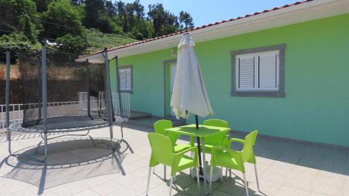 a patio with a table and an umbrella and chairs at Casa Além Vila in Armamar