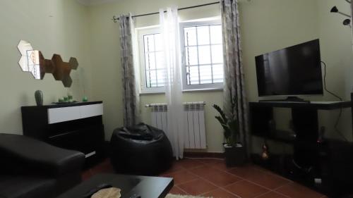 a living room with a large window and a television at Casa Além Vila in Armamar