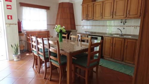 a kitchen with a table with chairs and a sink at Casa Além Vila in Armamar