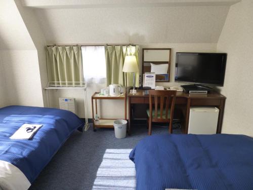 a hotel room with a bedroom with a bed and a desk at Suihoukaku Hotel in Fukuoka