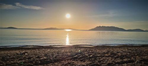a beach with the sun setting over the water at Apollon Hotel in Ancient Epidavros