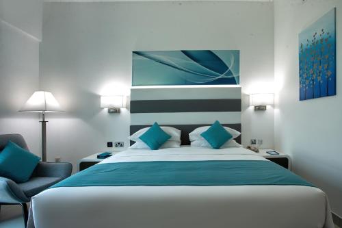 a bedroom with a large bed and a chair at City Avenue Al Reqqa Hotel in Dubai