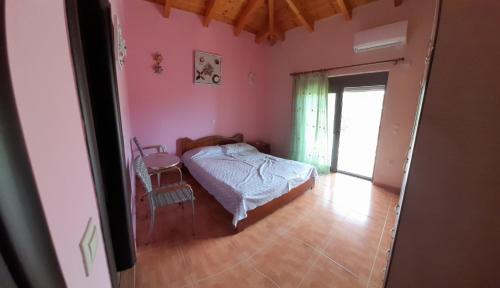 a bedroom with a bed in a room with pink walls at Stone Villa at Alyki Beach in Alikí