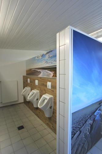 a bathroom with three urinals and a painting on the wall at StrandGutkoje auf dem Campingplatz Strandgut in Cuxhaven