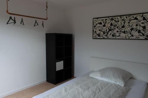 a bedroom with a bed and a black cabinet at Ferienwohnung Untersteinbach in Pfedelbach