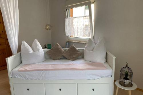 ein weißes Bett mit Kissen auf dem Zimmer in der Unterkunft Ferienhaus Bärbelstein / Wohnung Bärbelstein in Erlenbach