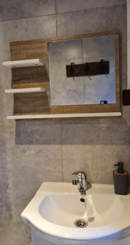 a bathroom with a white sink and a mirror at Domek pod lasem in Mikołajki