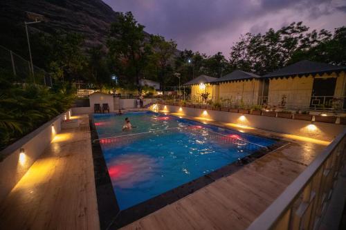 a pool with a person in the water at night at Indradhanush Hill Resort in Mulshi