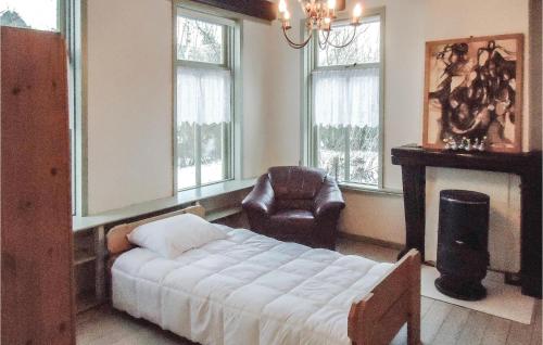 um quarto com uma cama, uma cadeira e janelas em 2 Bedroom Awesome Home In Surhuizum em Surhuizum