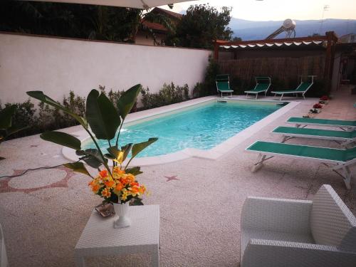 una piscina con sedie e un vaso di fiori di Bivano Villa Grazia a Fondachello