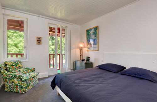 1 dormitorio con 1 cama, 1 silla y ventanas en Le Monde de Charlie, en Vichy