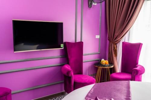 a room with purple walls and purple chairs and a tv at Lavie Hotel in Hanoi