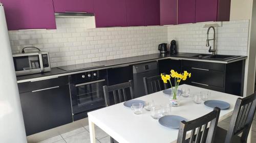 une cuisine avec une table blanche et des fleurs jaunes. dans l'établissement Gîte de la Voyette en Baie de Somme, à Bourseville