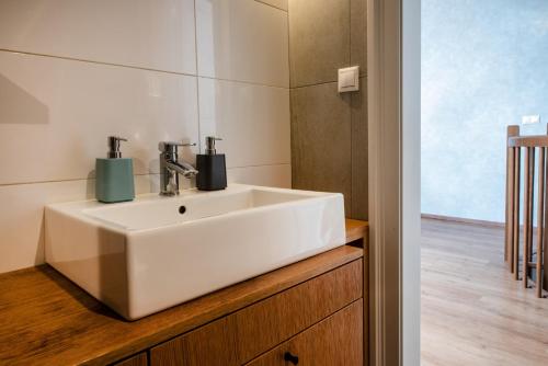 baño con lavabo blanco en una encimera de madera en ATRIO Apartments en Trenčín
