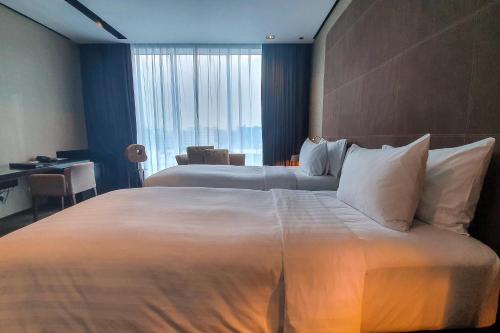 a hotel room with two beds and a desk at The Canvas Dubai - MGallery Hotel Collection in Dubai