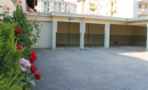 a building with a parking lot with red flowers at Hotel City in Chivasso